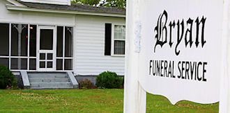 Bryan Funeral Service sign beside a white building with windows and green lawn