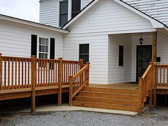 Wooden wheelchair-accessible ramp and steps leading to a white house entrance