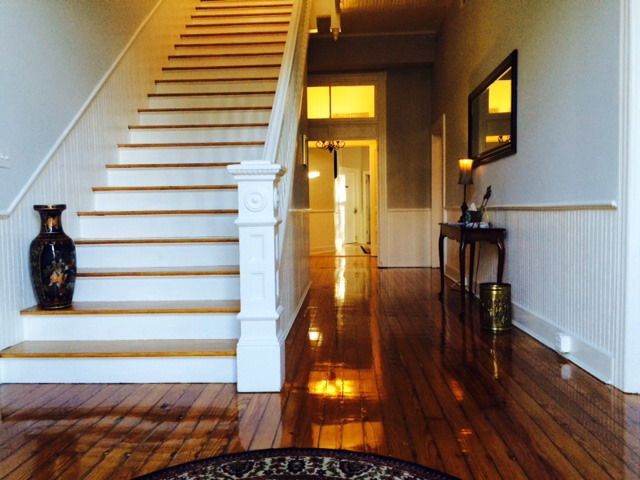 Bright foyer with a white staircase, polished wooden floor, and hallway table with mirror.