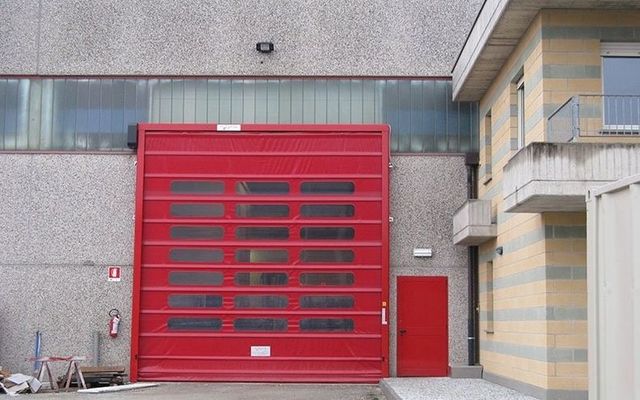 Una porta rossa del garage è aperta davanti a un edificio