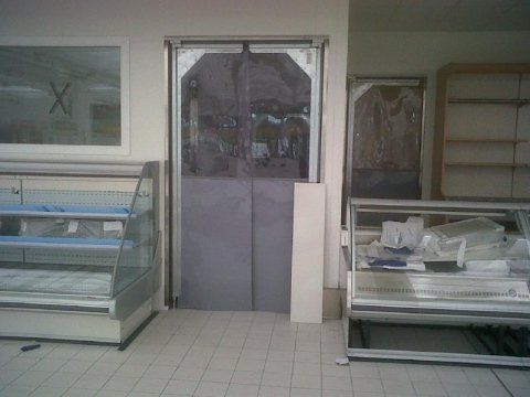 Una porta scorrevole grigia è appesa a una parete bianca.