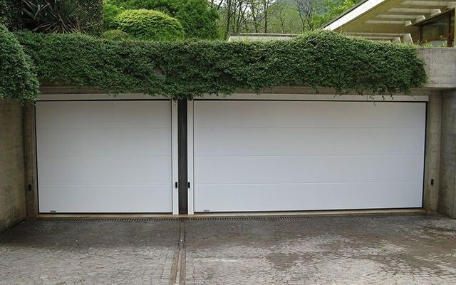 Una porta da garage bianca con l'edera che cresce sopra