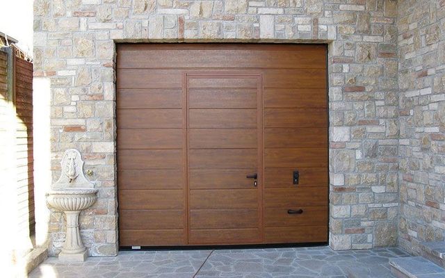 Una porta da garage in legno con un muro di pietra dietro