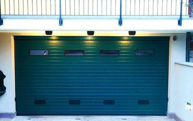 Una porta da garage verde con un balcone sullo sfondo