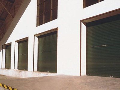 Una fila di porte da garage verdi su un edificio bianco