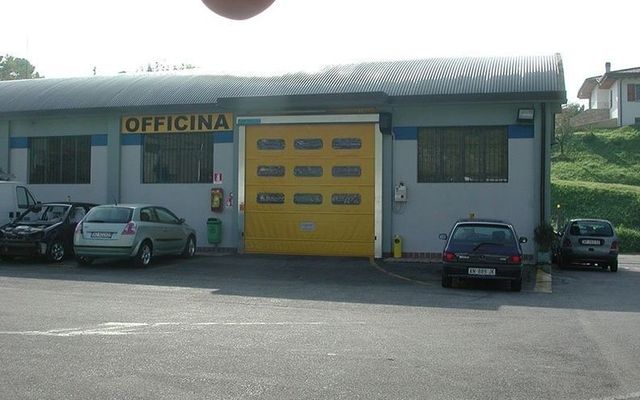 Le auto sono parcheggiate davanti a un edificio con la scritta officina
