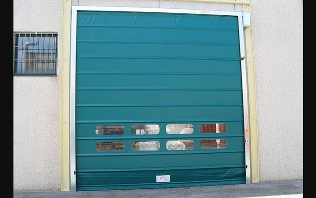 Una porta da garage verde è aperta su un edificio