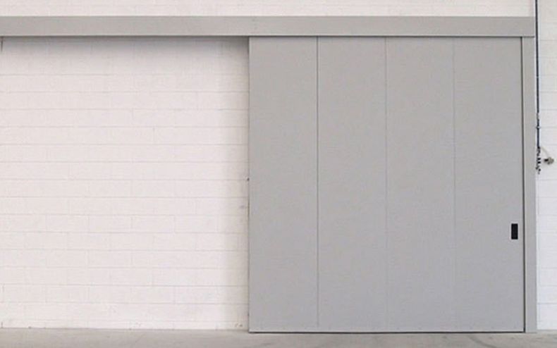 Un carrello elevatore verde è parcheggiato in un garage accanto a una grande porta bianca.