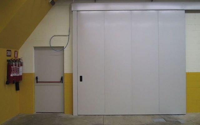Una porta scorrevole bianca in un edificio accanto a un estintore