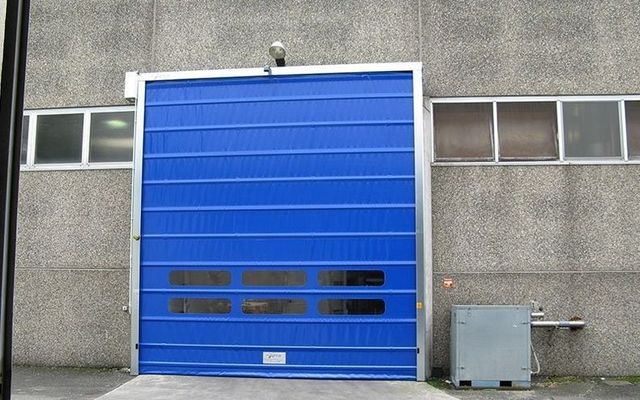 Una porta da garage blu è aperta davanti a un edificio