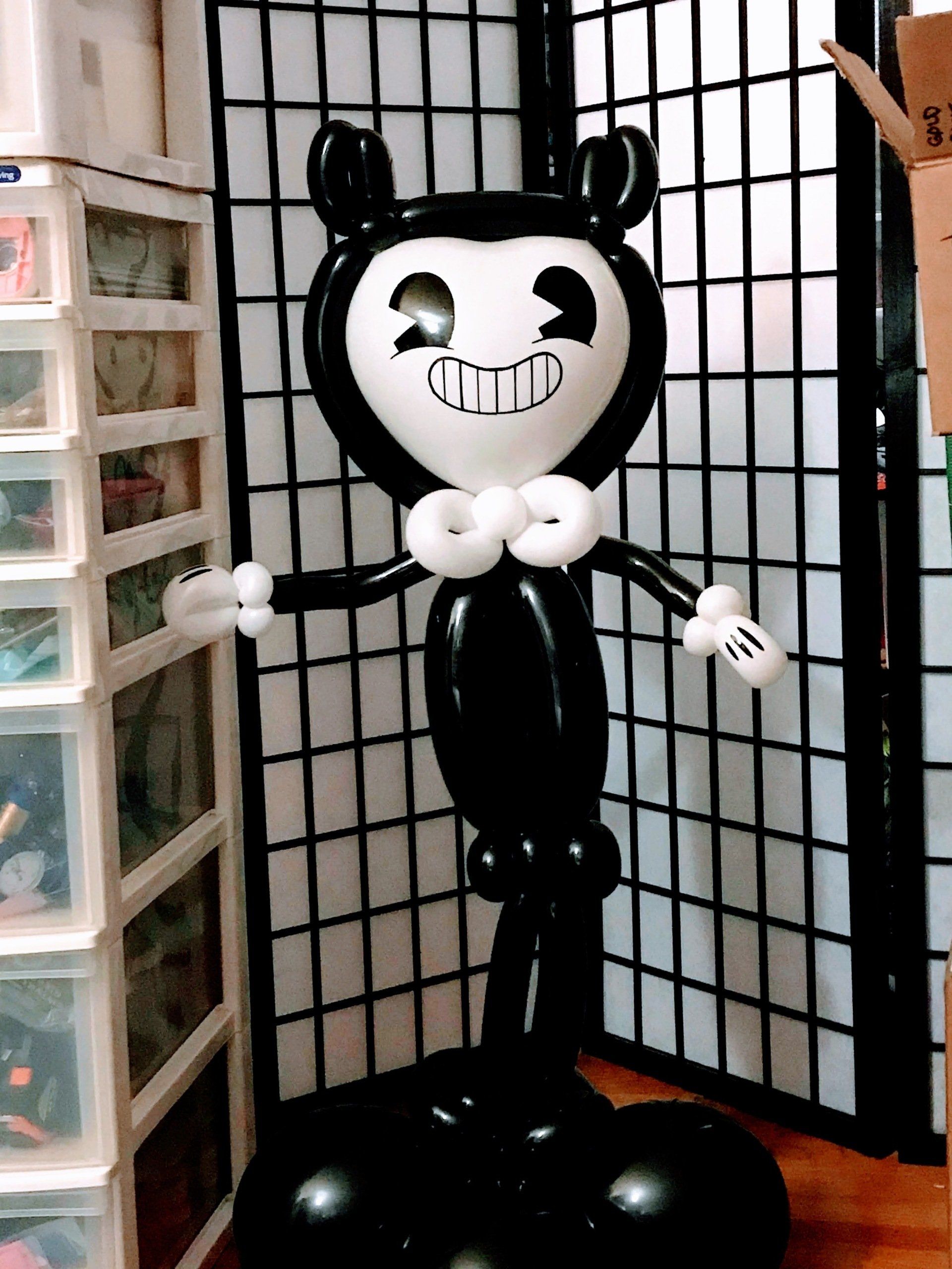 Black and white balloon sculpture of Bendy, a cartoon character, standing indoors.