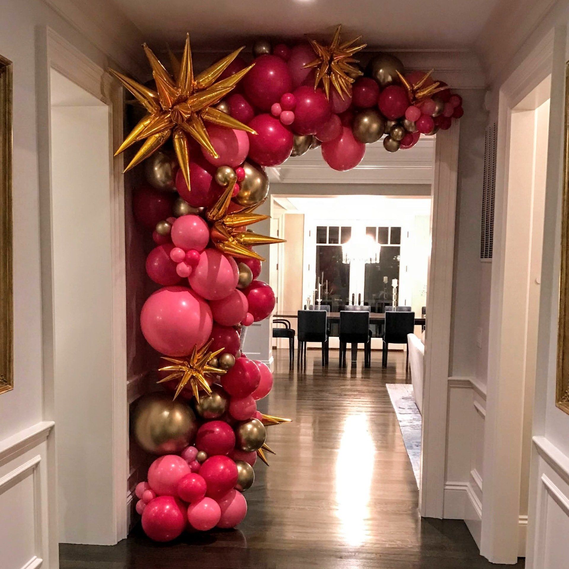 A pink and gold organic balloon arch with gold foil starbursts balloons