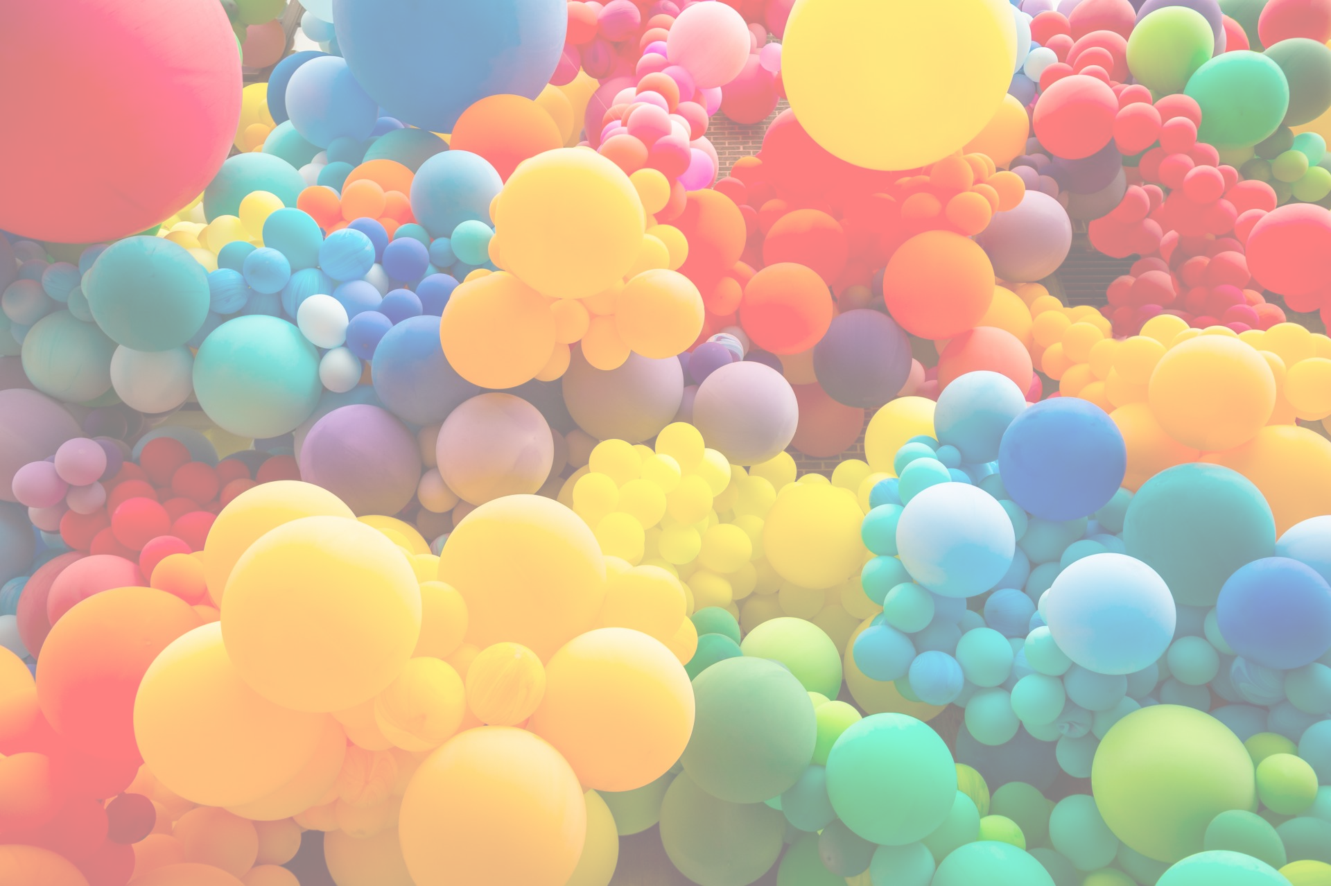 A vibrant, colorful cluster of organic balloon design in a rainbow of colors suggesting a whimsical, festive, balloon display.