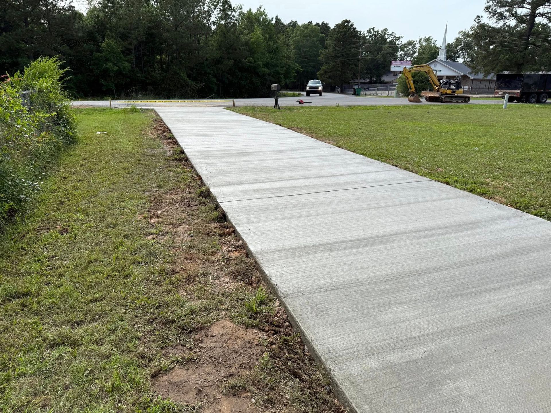 A long concrete walkway going through a grassy field.