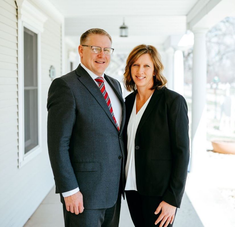 A man and a woman are standing next to each other on a porch.