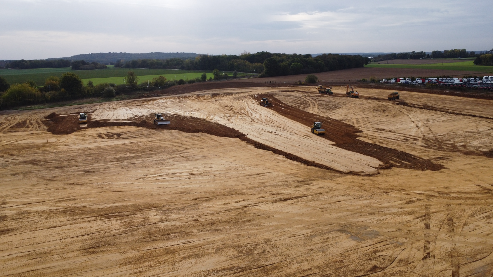 Une vue aérienne d'un champ de terre avec des tracteurs qui y travaillent.