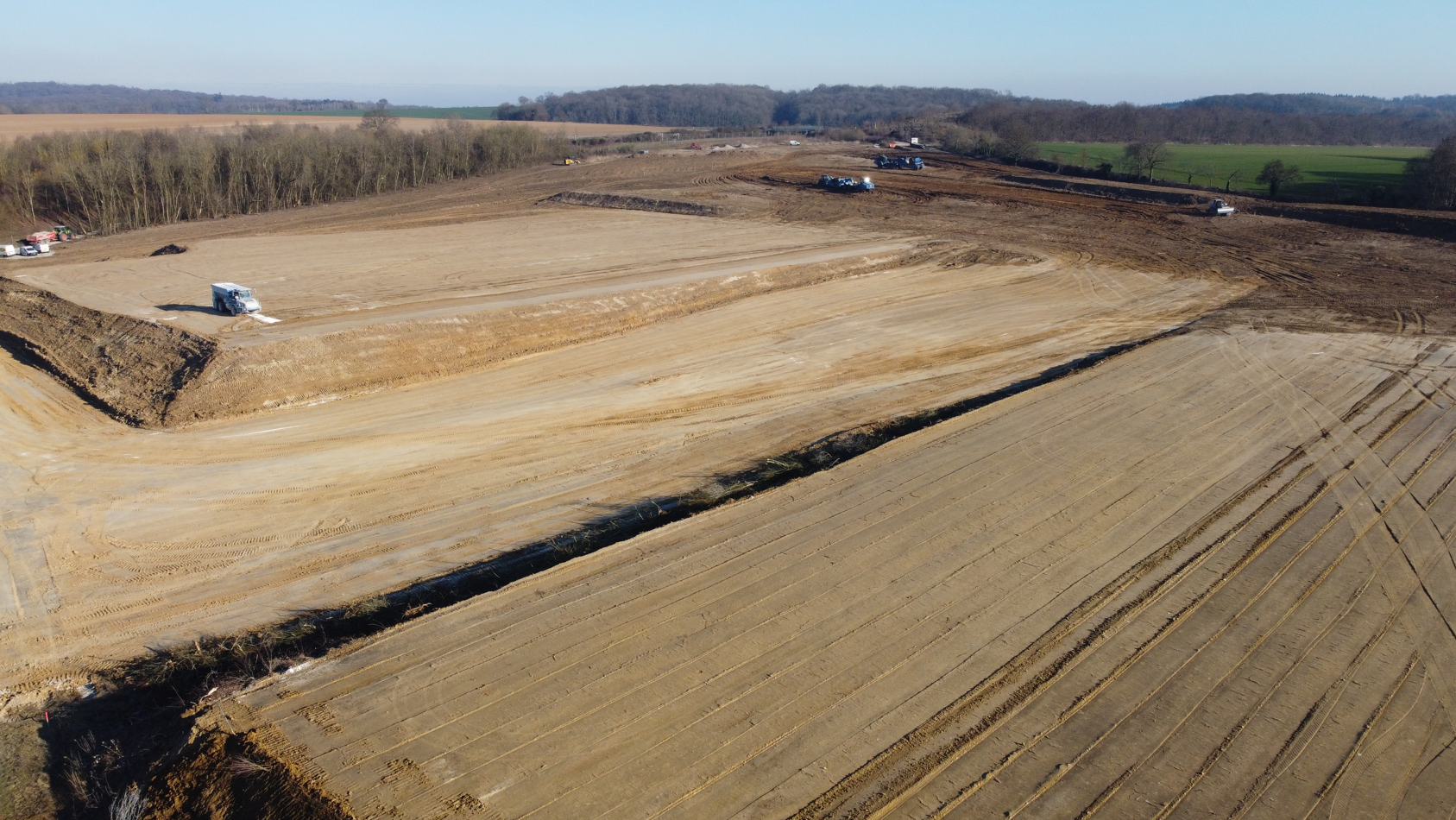Une vue aérienne d'un champ de terre avec des arbres en arrière-plan.