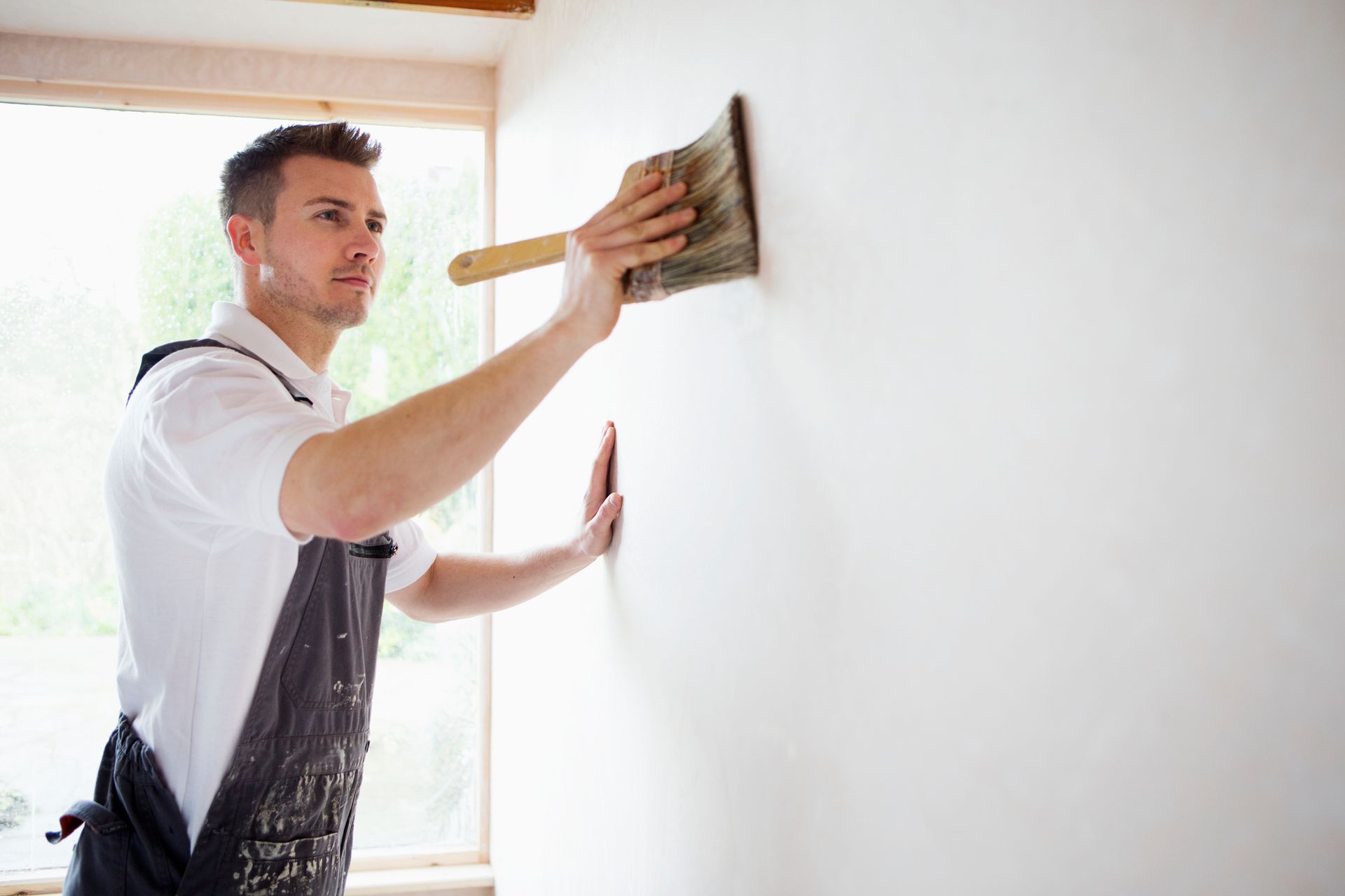 A man is painting a wall with a brush.