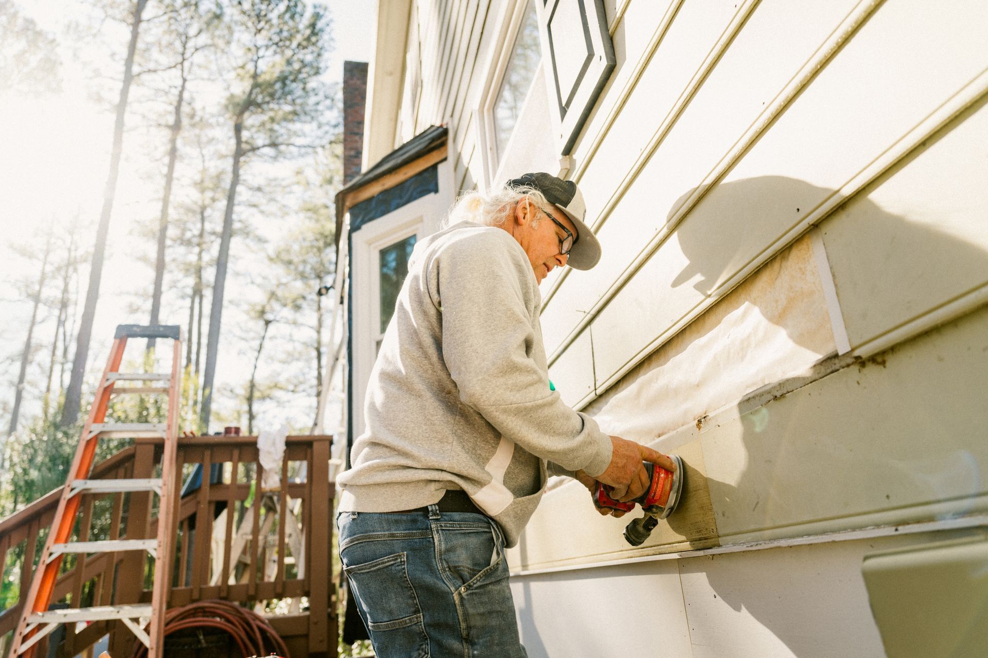 A man is working on the side of a house with a saw.