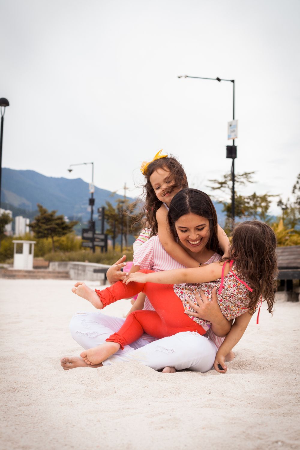 A mom and two daughters playing together on the sand