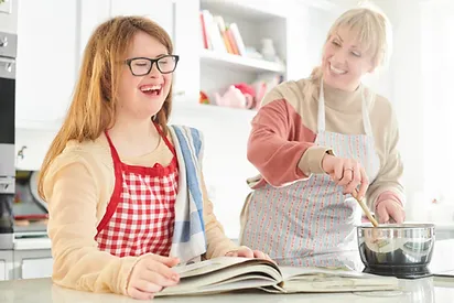 Mother and daughter with downs syndrome cooking and smiling