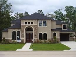 Large beige two-story house with arched entry, front lawn, and attached garage