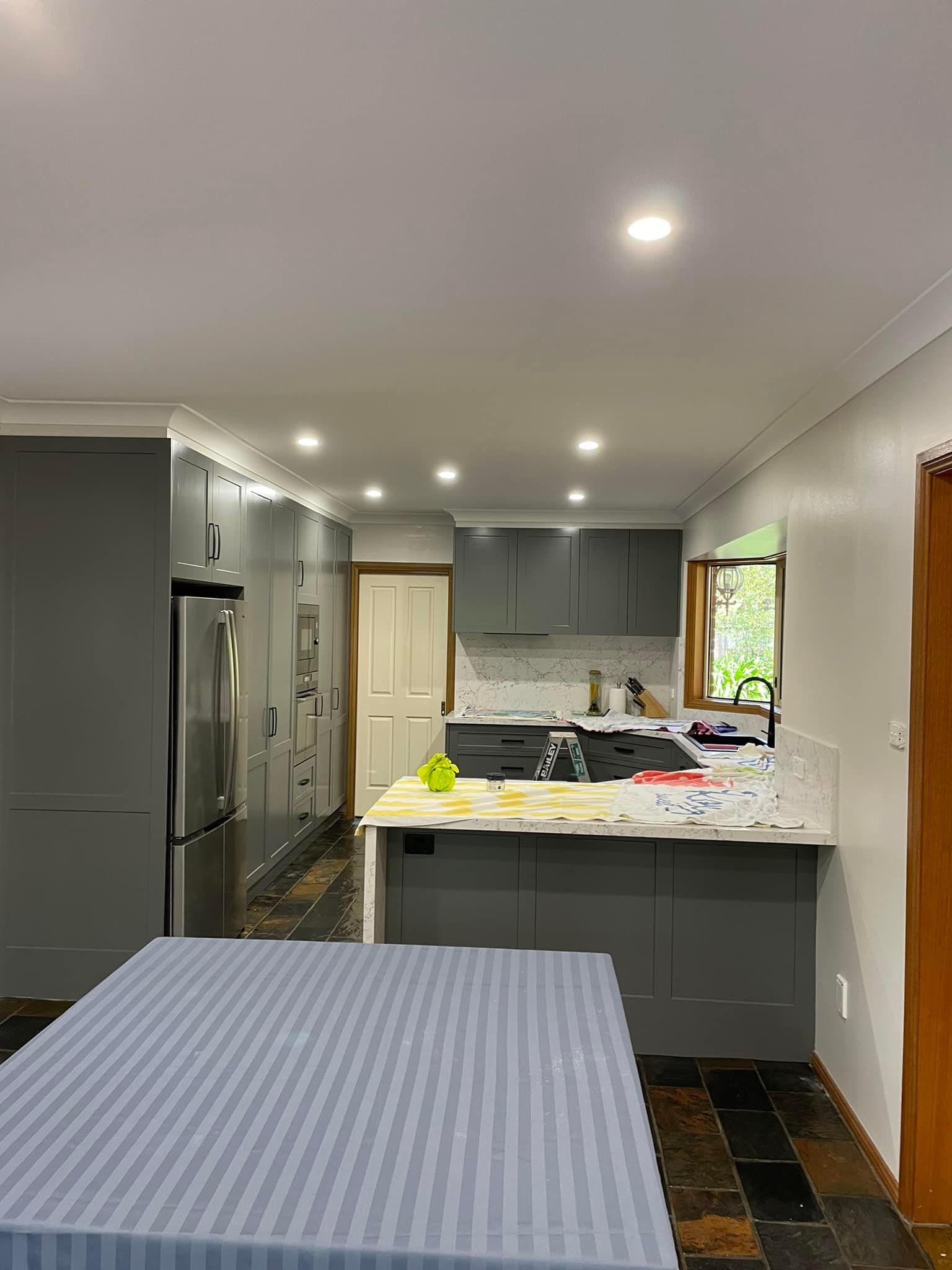 A Kitchen With Gray Cabinets and a Blue Table Cloth — Karl Witt Painter & Decorator In Oak Flats, NSW