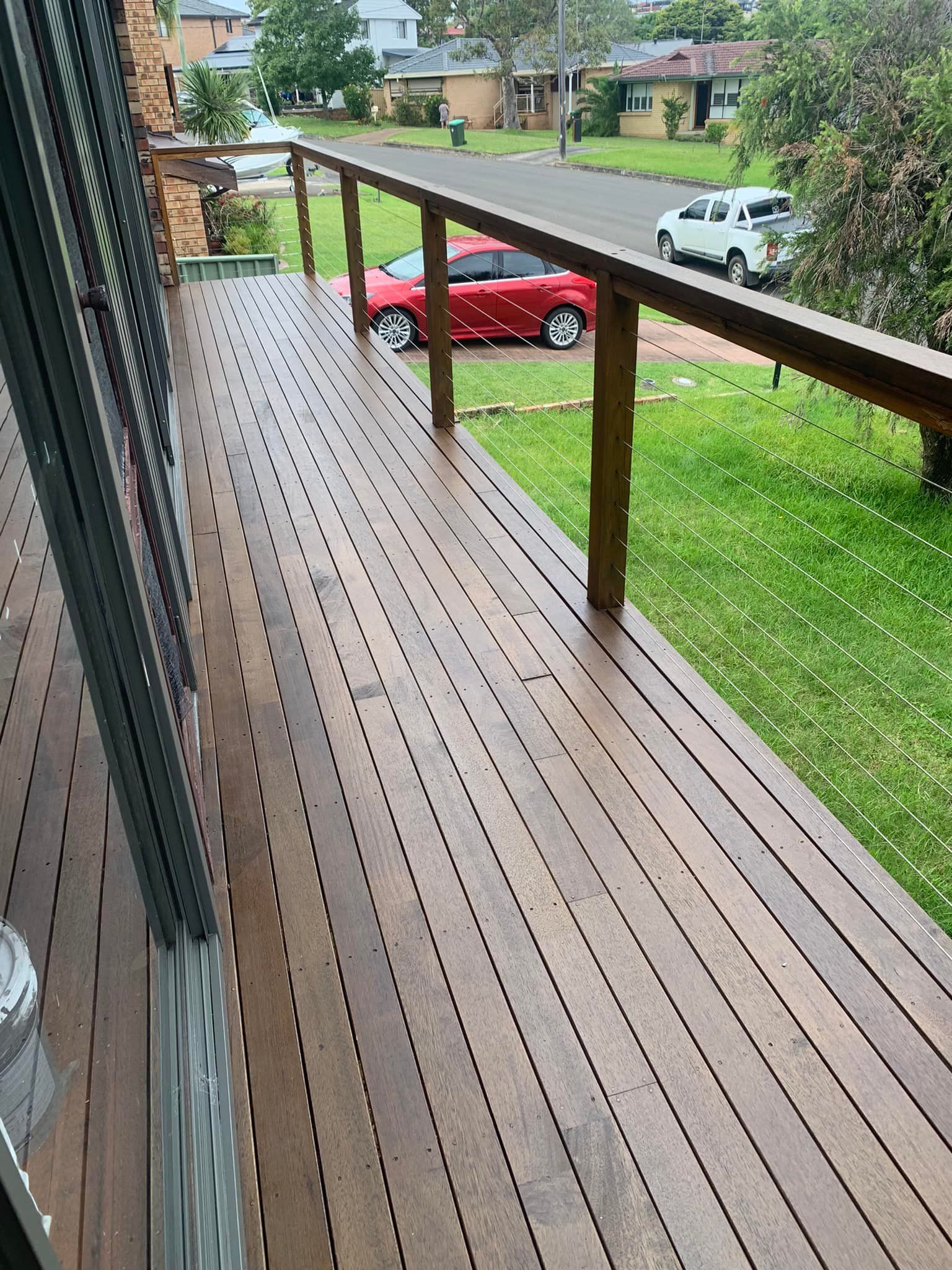 A Red Car is Parked on the Side of the Road on a Wooden Deck — Karl Witt Painter & Decorator In Shell Cove, NSW