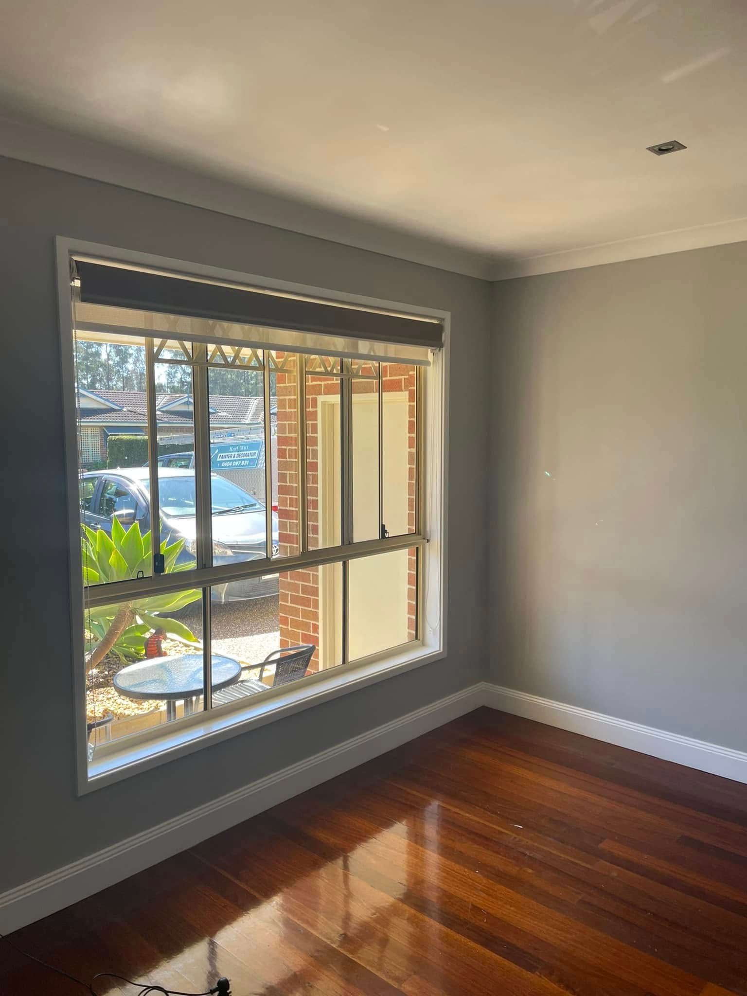 An Empty Room With a Large Window and a Wooden Floor — Karl Witt Painter & Decorator In Shell Cove, NSW