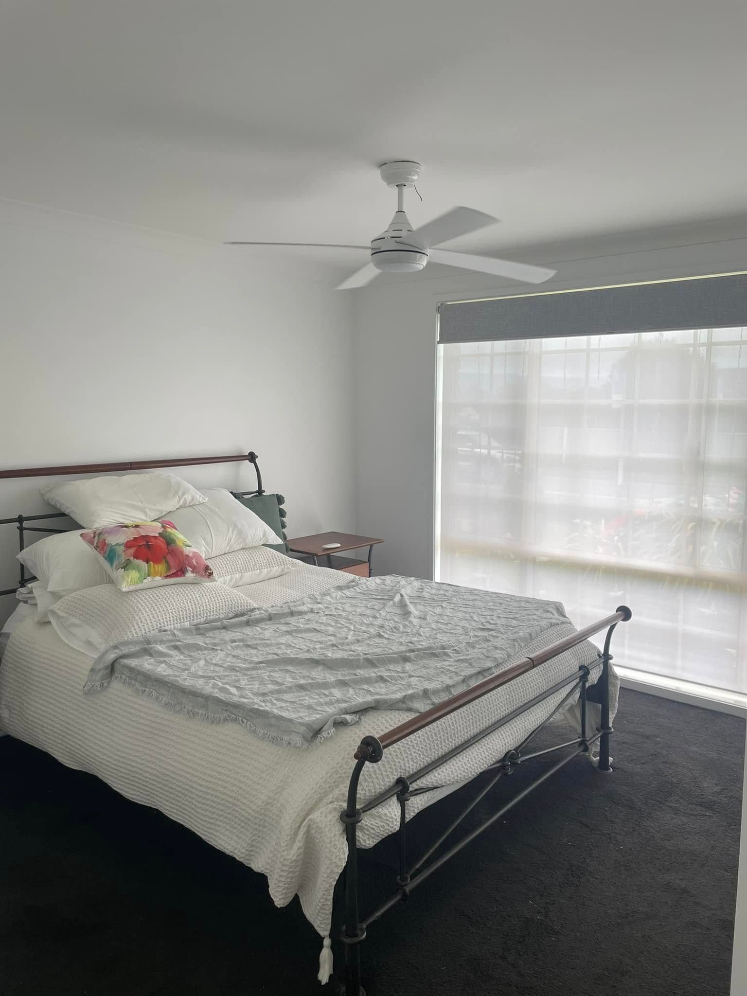 A Bedroom With a Bed , Ceiling Fan , and Window — Karl Witt Painter & Decorator In Kiama, NSW