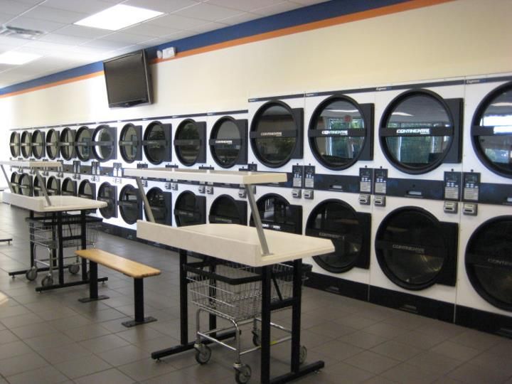 A laundromat with a lot of washers and dryers stacked on top of each other.