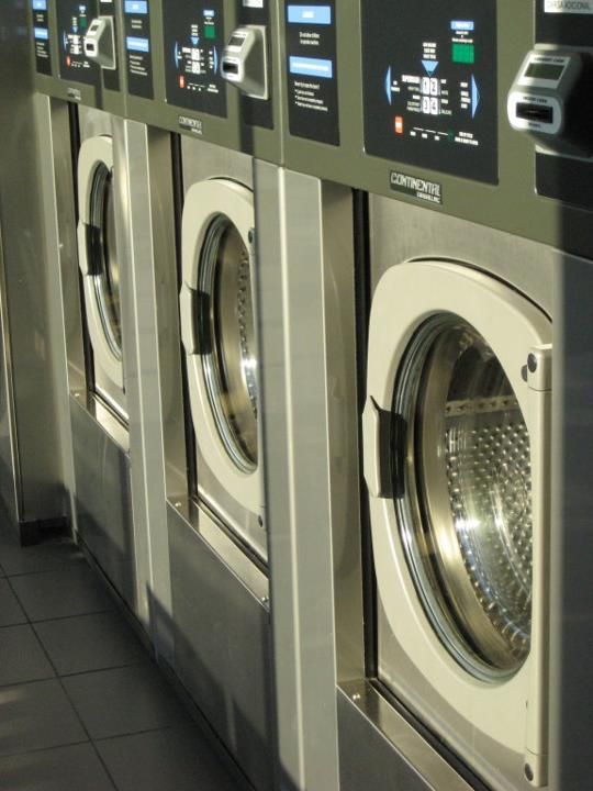 A row of washing machines are lined up in a laundromat