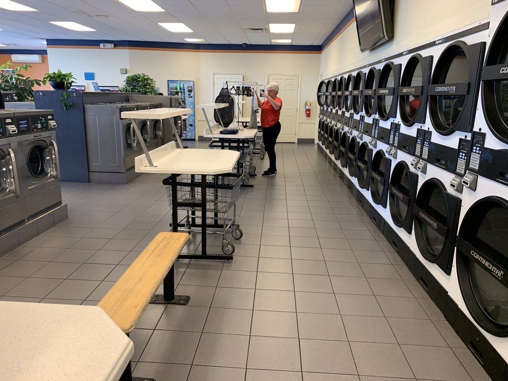 A woman is standing in a laundromat looking at her phone.