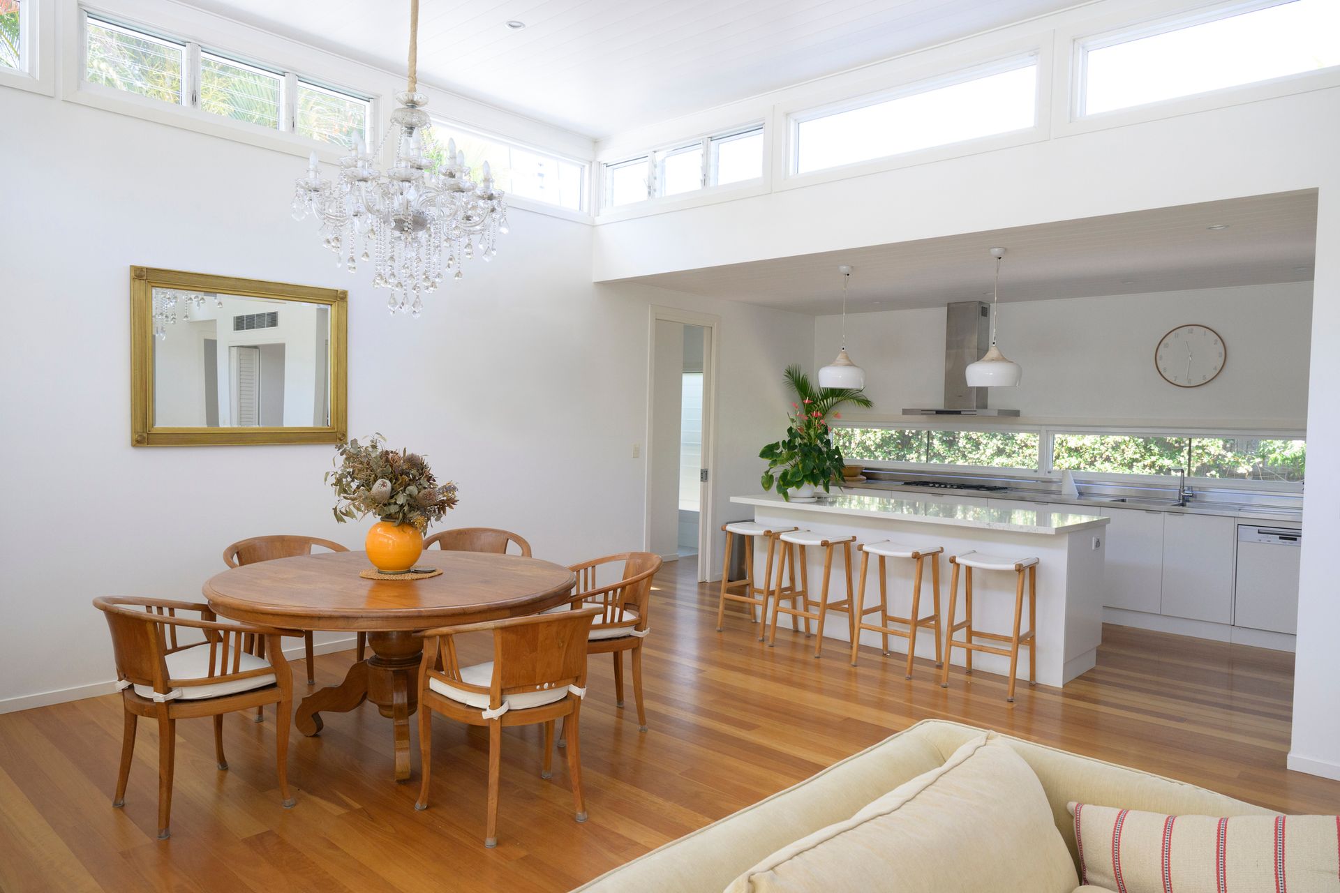 Dining room with wooden table, chairs, and kitchen with a white island.