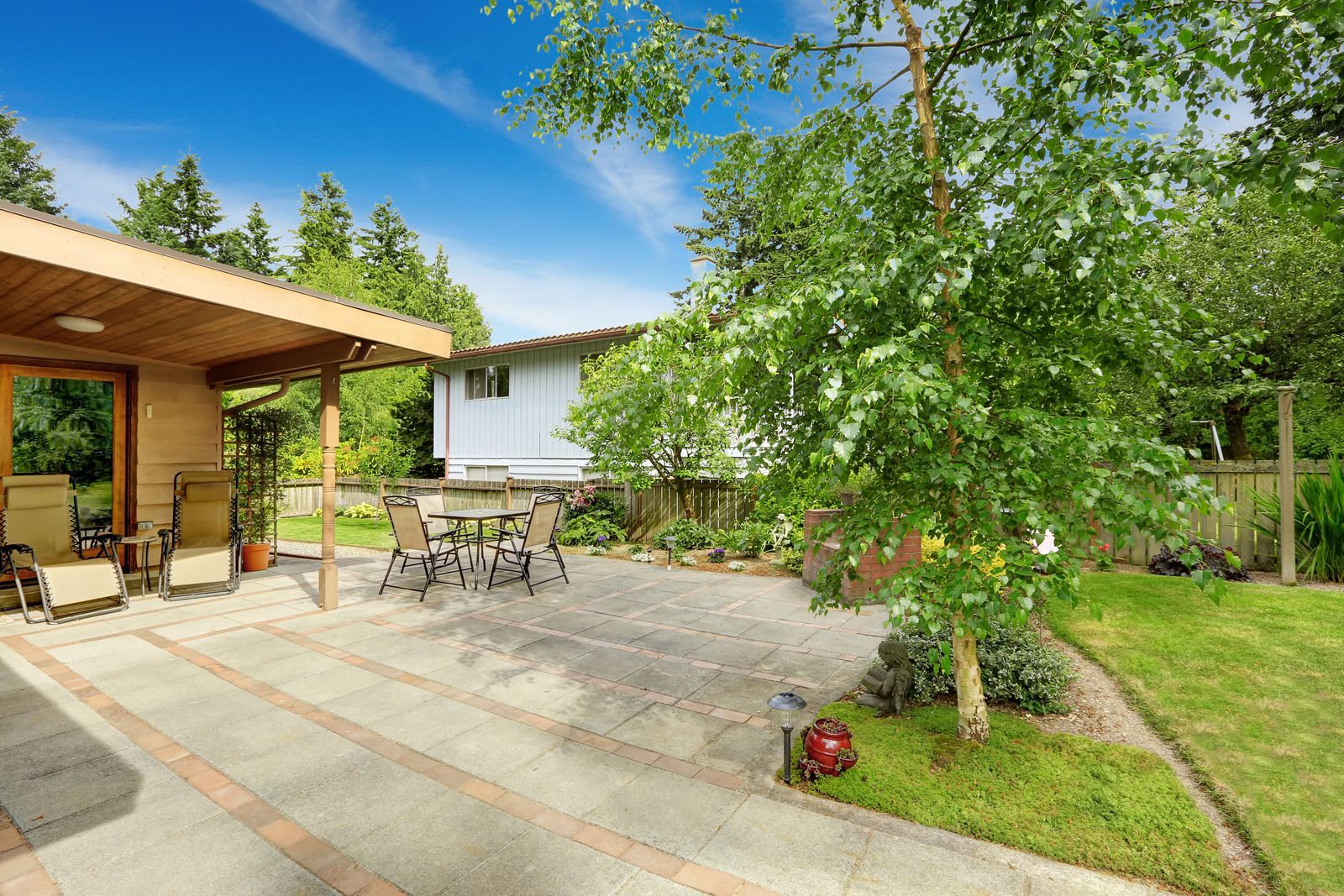 A patio with a table and chairs in front of a house.
