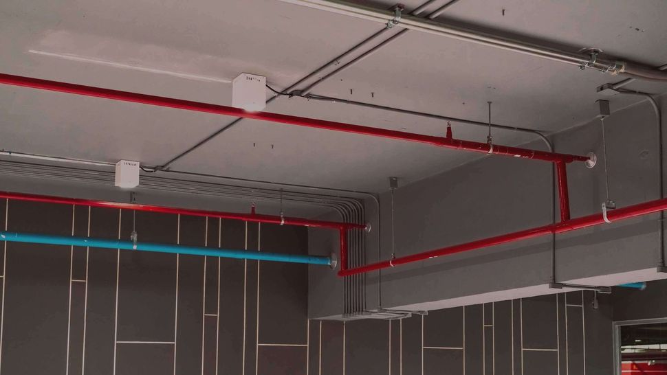 Ceiling with red and blue exposed pipes in an unfinished room