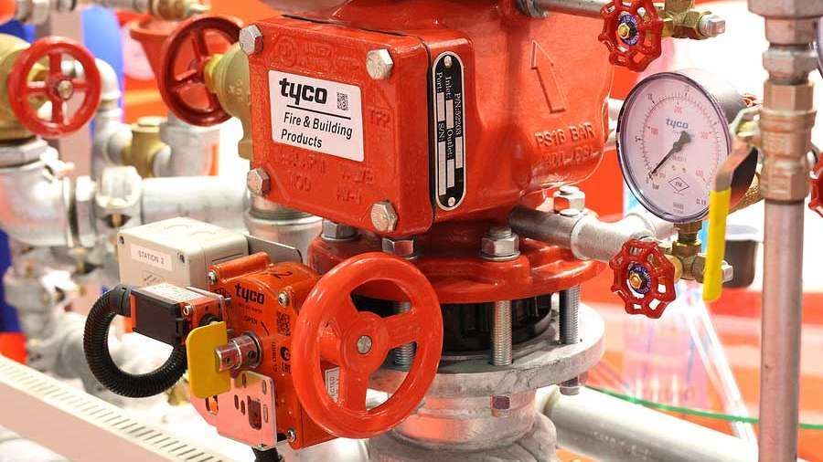 Red industrial valve assembly with gauges and handwheels on piping.