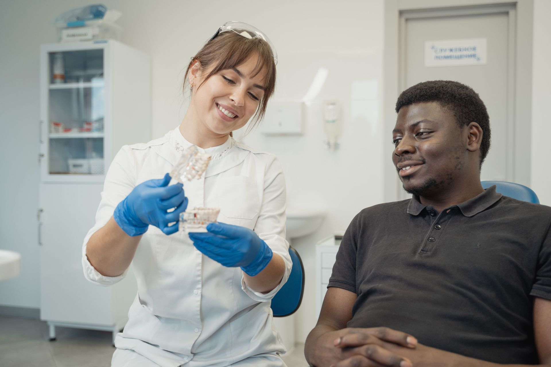 Dentist and patient both sitting down in dental office with dentist showing model of gums and teeth