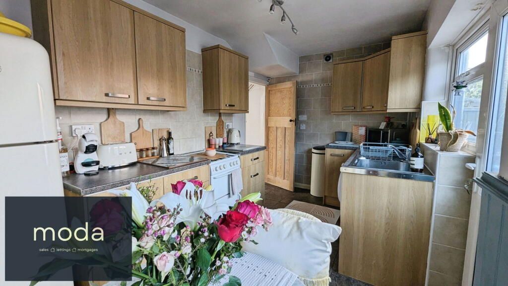 Kitchen with wooden cabinets, white fridge, and dining table with flowers.