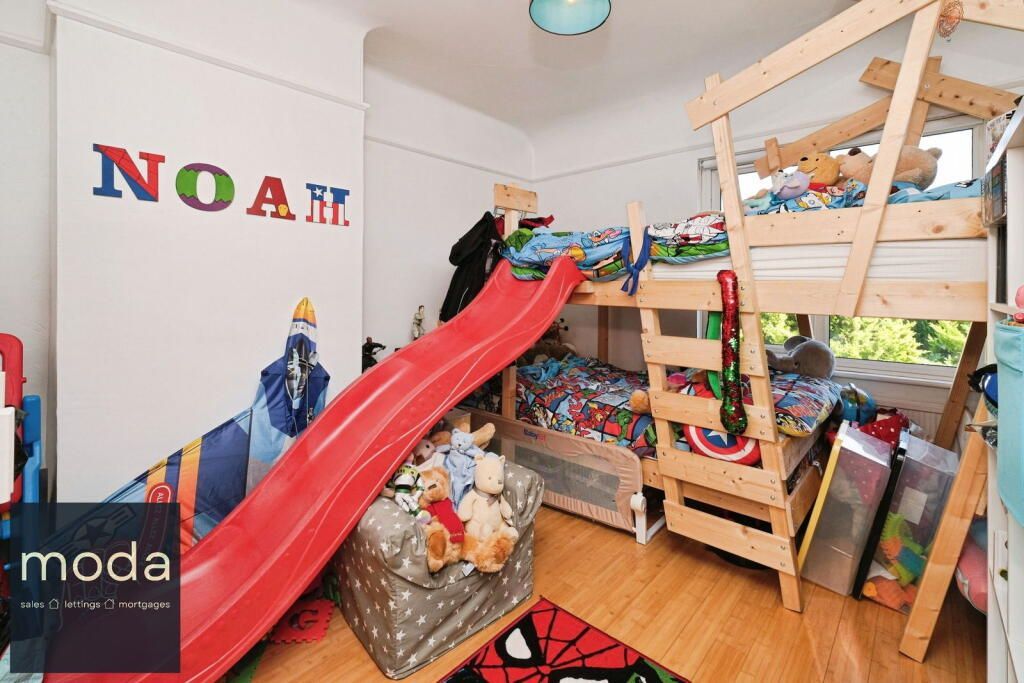 A child's bedroom with a bunk bed, a red slide, and colorful decorations including a name.