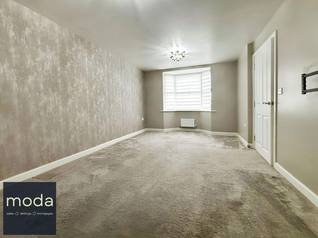 Empty bedroom with textured wallpaper, bay window, and white door.
