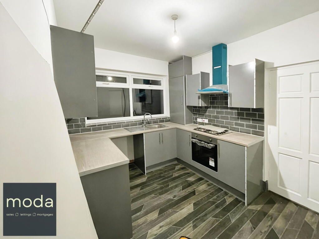 Gray kitchen with cabinetry, brick backsplash, wood-look floor, and aqua range hood.