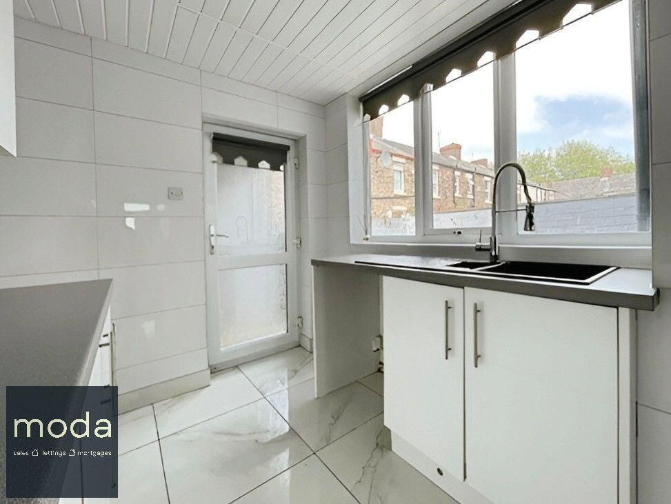 White kitchen with window, door, cabinets, and sink.