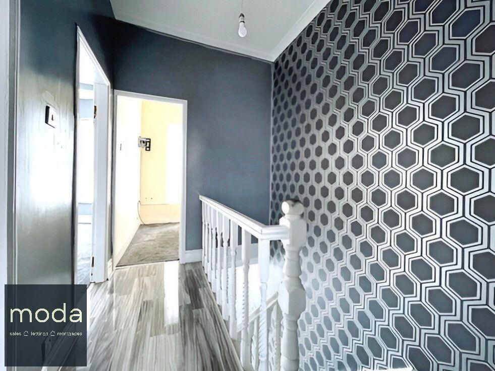 Hallway with gray walls, geometric wallpaper, and wooden flooring.
