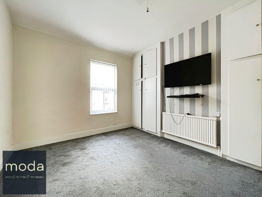 Bedroom with gray carpet, striped accent wall, TV, and built-in storage.