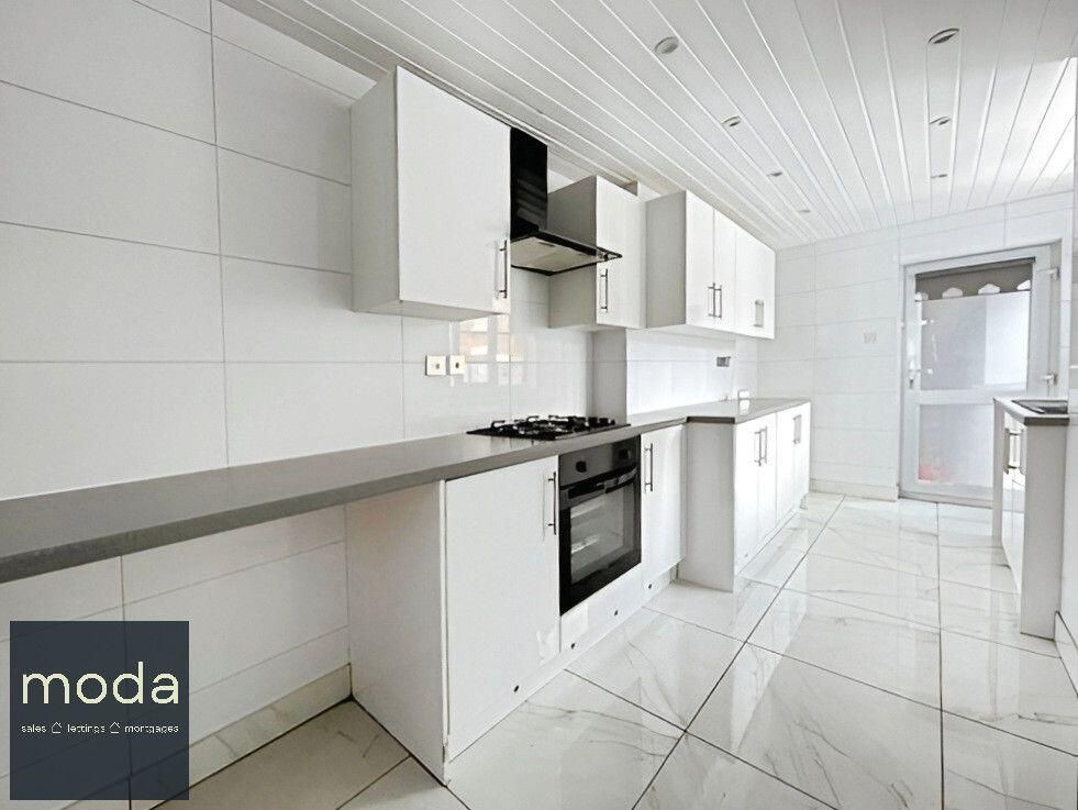 White kitchen with cabinets, counter, appliances. Door to right.