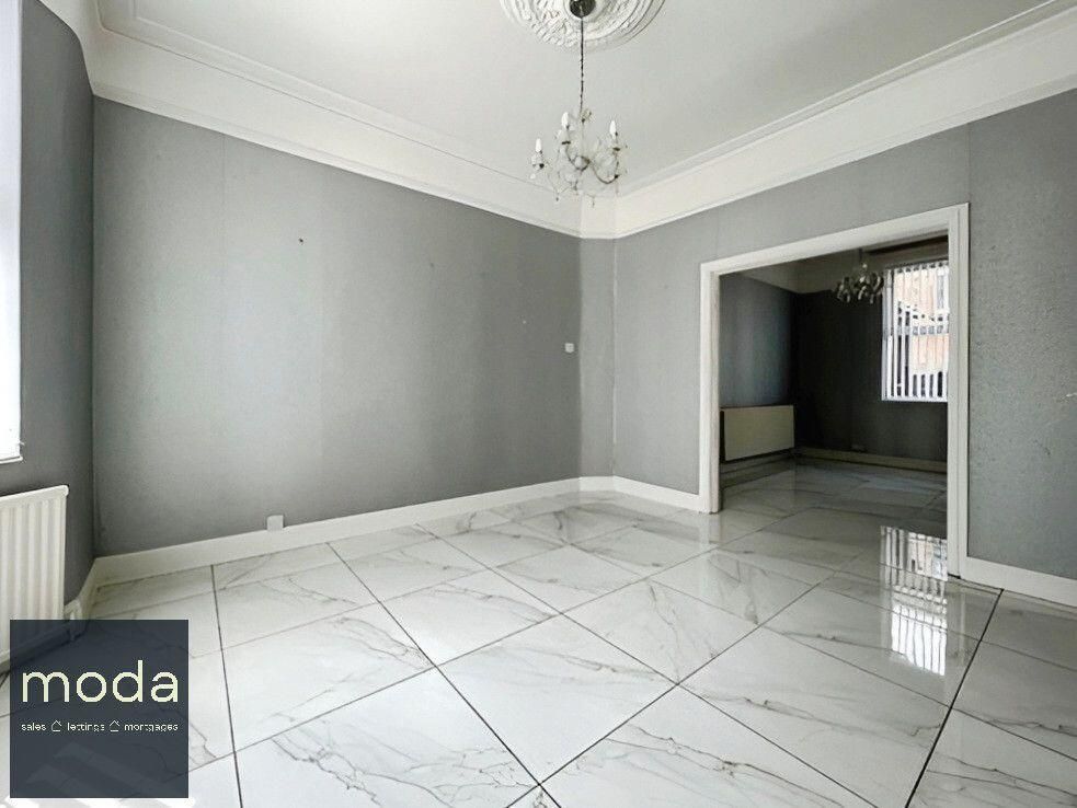 Empty room with grey walls, white tiled floor, and an opening to another room.