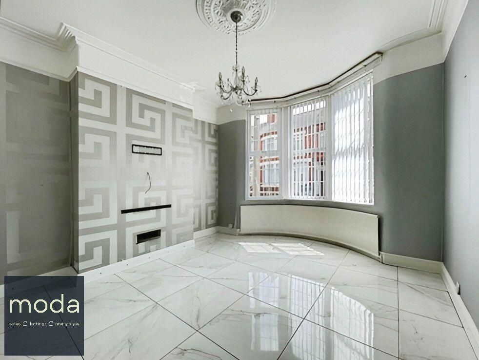 Empty room with marble floors, patterned accent wall, bay window, and chandelier.