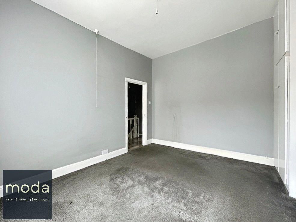 Empty room with gray walls and carpet, door leading to stairs on the wall, built-in storage.