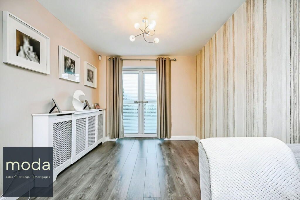 Bedroom with white furniture, framed photos, and patterned wallpaper, with a doorway to a balcony.